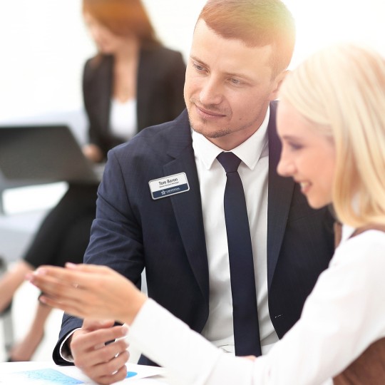 Bildet viser en resepsjonist med Badgepoint® profesjonelle navneskilt, som hjelper en dame.