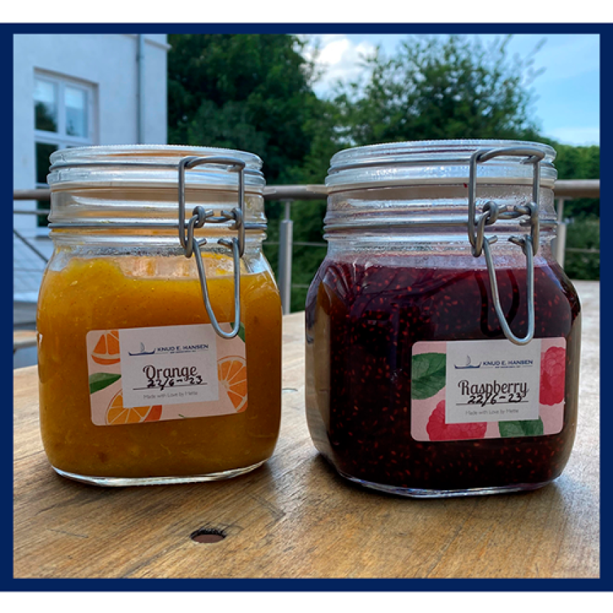 To syltetøyglass med appelsin- og bringebærmarmelade, med etiketter hvor det står Orange og Raspberry.