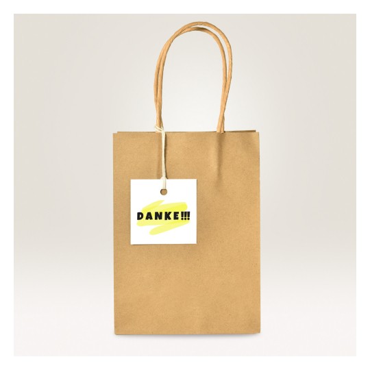 Bildet viser en brun papirpose med en merkelapp som sier 'DANKE!!!' med et gult penselstrøkdesign.