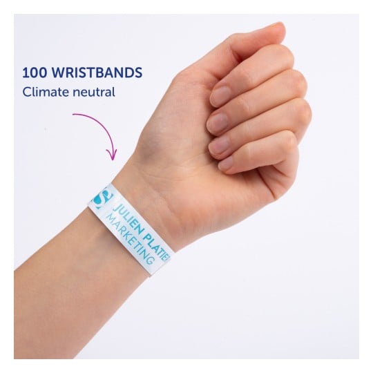 Bildet viser en persons hånd som har på seg et armbånd med teksten '100 WRISTBANDS Climate neutral' og 'JULIEN PLATTER MARKETING' trykket på det.