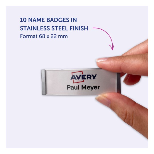 Bildet viser en hånd som holder et navneskilt i rustfritt stål finish, med teksten 'Avery' og navnet 'Paul Meyer'. Det fremhever at det finnes 10 navneskilt tilgjengelig i det spesifiserte formatet på 68 x 22 mm.