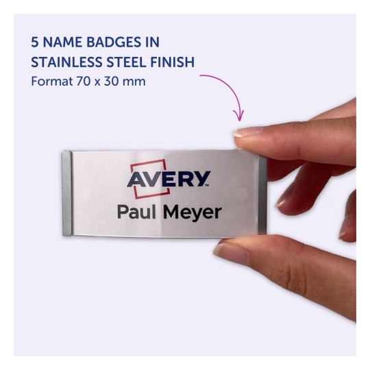 Bildet viser en person som holder et navneskilt med teksten 'Avery Paul Meyer.' Det indikerer at produktet er et sett med fem navneskilt i en rustfritt stål finish, med målene 70 x 30 mm.