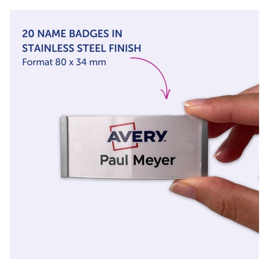 Bildet viser en hånd som holder et navneskilt med navnet 'Paul Meyer' og logoen 'Avery'. Skiltet har en finish i rustfritt stål, måler 80 x 34 mm, og det er oppført 20 skilt i dette formatet.