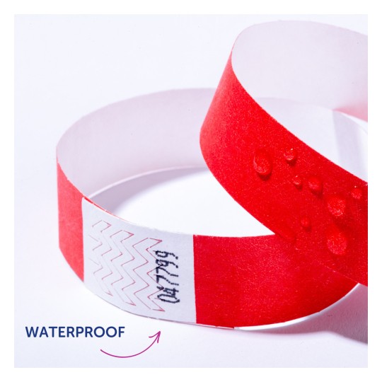 Bildet viser et rødt vanntett armbånd med vanndråper på. Det er sikksakkmønstre og tekst på en hvit stripe av båndet.