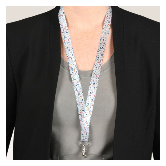 Bildet viser en person som har på seg en svart blazer over en grå skjorte, med et fargerikt blomstrete nøkkelbånd rundt halsen som holder et ID-kort.