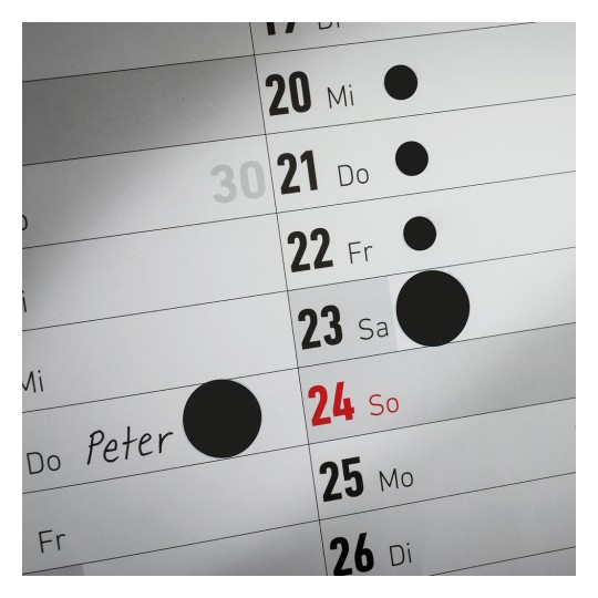 En kalenderblads side viser datoer med 'Peter' skrevet på den 24. Den markerer flere andre datoer med svarte sirkler.