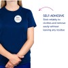 Bildet viser en person som har på seg en marineblå t-skjorte med en selvklebende navnelapp som sier "B. Carlos MARKETING DIRECTOR". Teksten til høyre fremhever det selvklebende trekket, med fokus på påliteligheten og at den kan fjernes uten å etterlate rester.