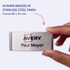 Bildet viser 10 navneskilt i en finish av rustfritt stål, med logoen 'Avery' og navnet 'Paul Meyer'. Skiltene blir vist i en persons hånd.