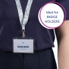 Bildet viser en person med en mørk skjorte og en nøkkelbånd med et ID-kort som leser 'MELINA DOPPER' og 'Designer.' Nøkkelbåndet har et fargerikt blomsterdesign. En tekstboble på bildet sier 'Ideell for KORTHOLDERE.'
