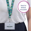 Bildet viser en person som har på seg en nakkestropp med et fargerikt tropisk design. Et skilt er festet, som viser navnet 'Melina Doppler' og tittelen 'Designer.' Bakgrunnen har en sirkelformet tekst 'Ideell for KORTHOLDERE.'