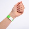 Et nærbilde av en hånd med et grønt armbånd på håndleddet. Armbåndet har en hvit del med et sikksakkmønster og ser ut til å være merket med et nummer.