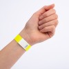 Dette bildet viser en hånd med et gult armbånd som har en hvit seksjon med et sikksakkmønster og et nummer på.
