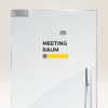 Bildet viser en dør med et skilt som lyder 'MEETING RAUM III' ved siden av en gul stolpe og logoen til 'Avery Zweckform'.