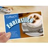 Bildet viser et reklamekort for en kaffebar med en cappuccino med skum og kakaopulver. På kortet står navnet 'CoffeeCo' og ordet 'Fantastico' fremhevet. Kontaktinformasjon og en nettside er også synlig.