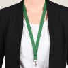 Bildet viser en person iført en svart blazer over en hvit skjorte, med en grønn snor rundt halsen. Snoren har en klips nederst, sannsynligvis for å holde en ID eller et skilt.