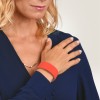 Bildet viser en kvinne med blondt hår som har på seg en mørk blå bluse, med en hånd plassert på skulderen. Hun har et tynt halskjede og bærer et oransje armbånd på håndleddet.